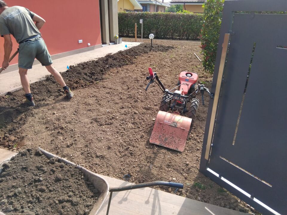 Preparazione del terreno con una motozappa vicino a una casa